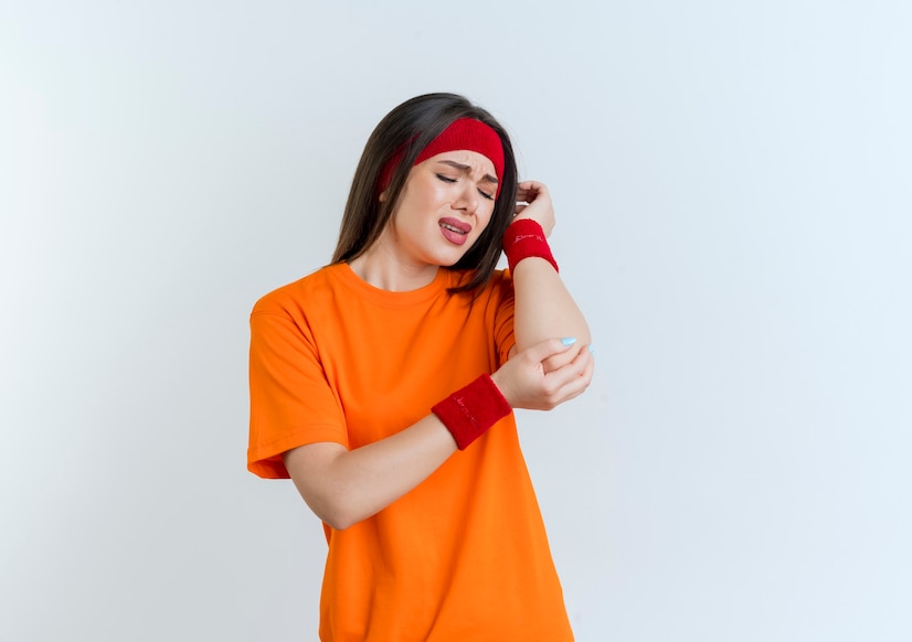 aching-young-sporty-woman-wearing-headband-wristbands-holding-looking-elbow-isolated_141793-68751 Menyiasati Nyeri Sendi di Usia Muda: Mengenal Gejala dan Penanganannya